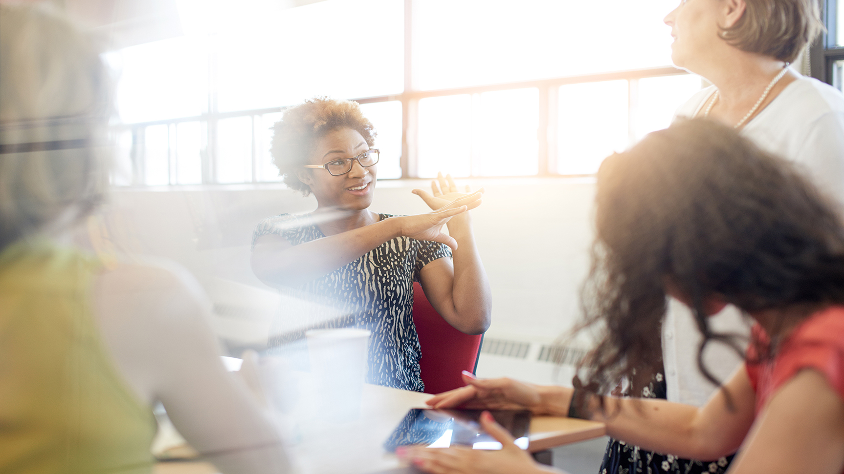 Candid picture of a female boss and business team collaborating. Filtered serie with light flares, bokeh, warm sunny tones.