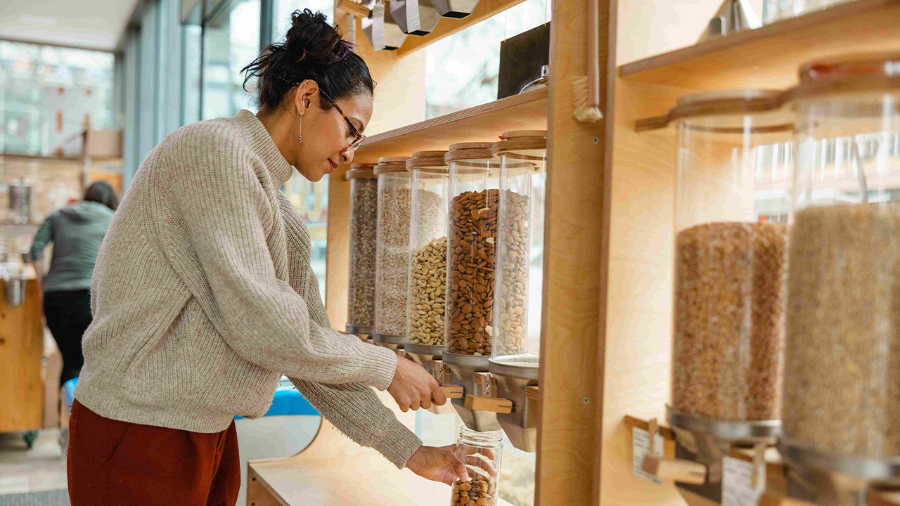 Female Using A Nuts Dispenser In A Zero Waste Store