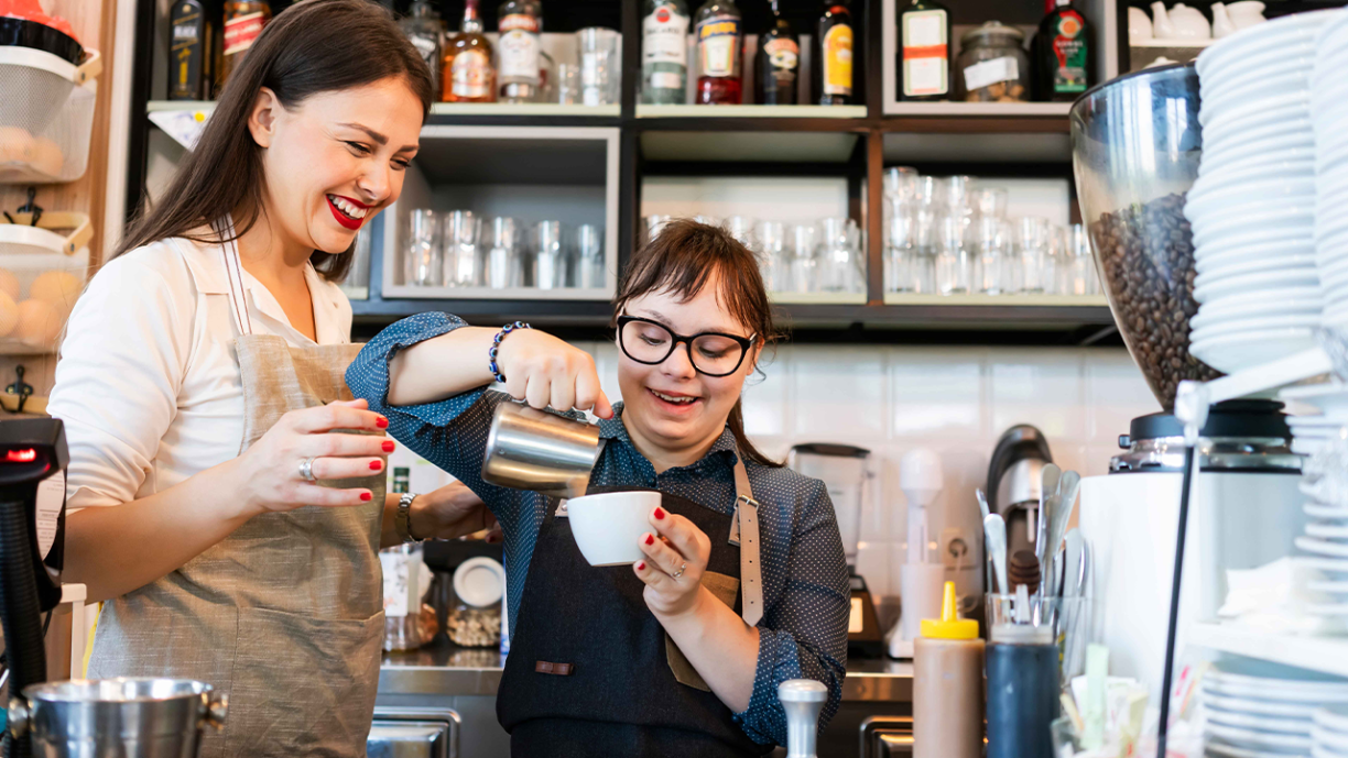 How to attract and retain talent in the hospitality and leisure industry - Young woman with Down Syndrome working at cafe preparing coffee