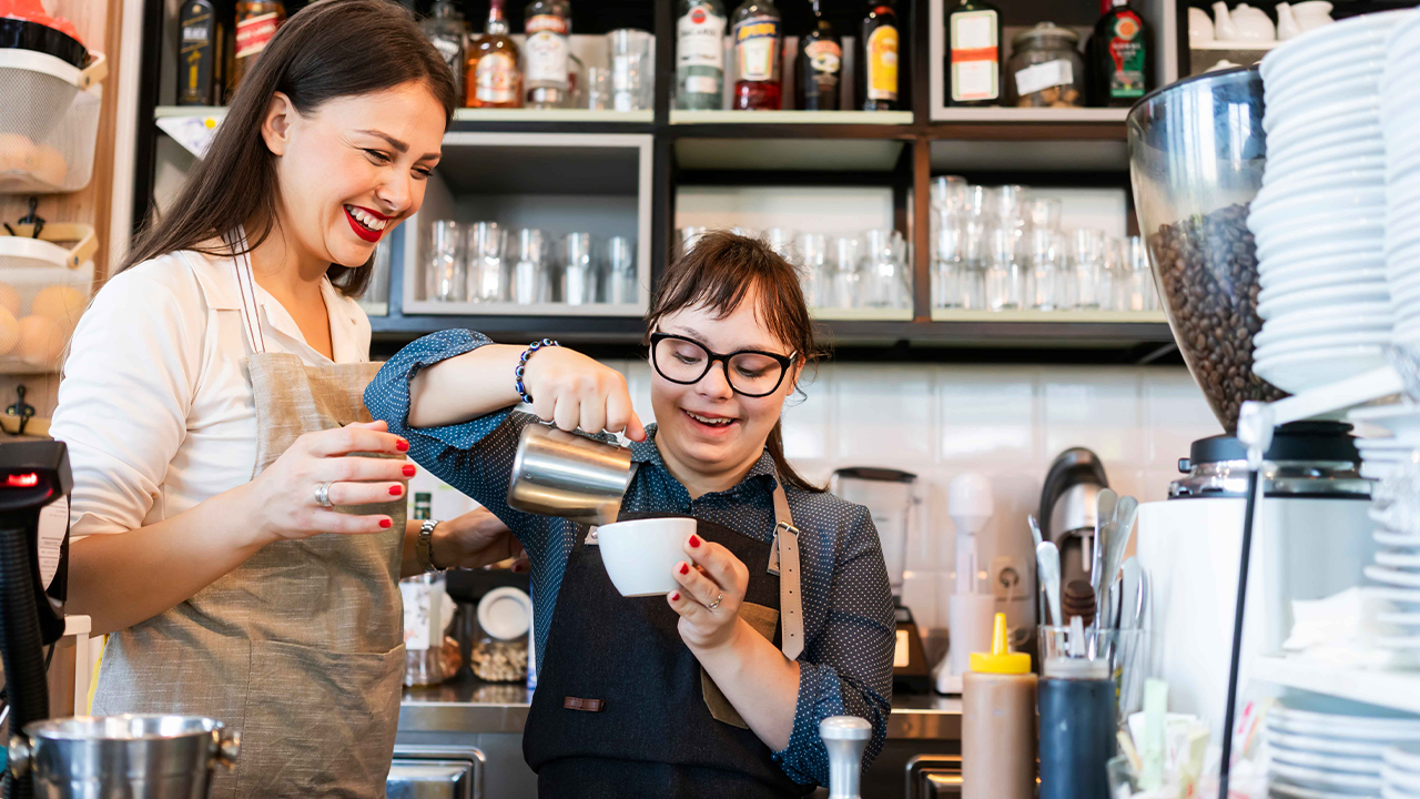 How to attract and retain talent in the hospitality and leisure industry - Young woman with Down Syndrome working at cafe preparing coffee