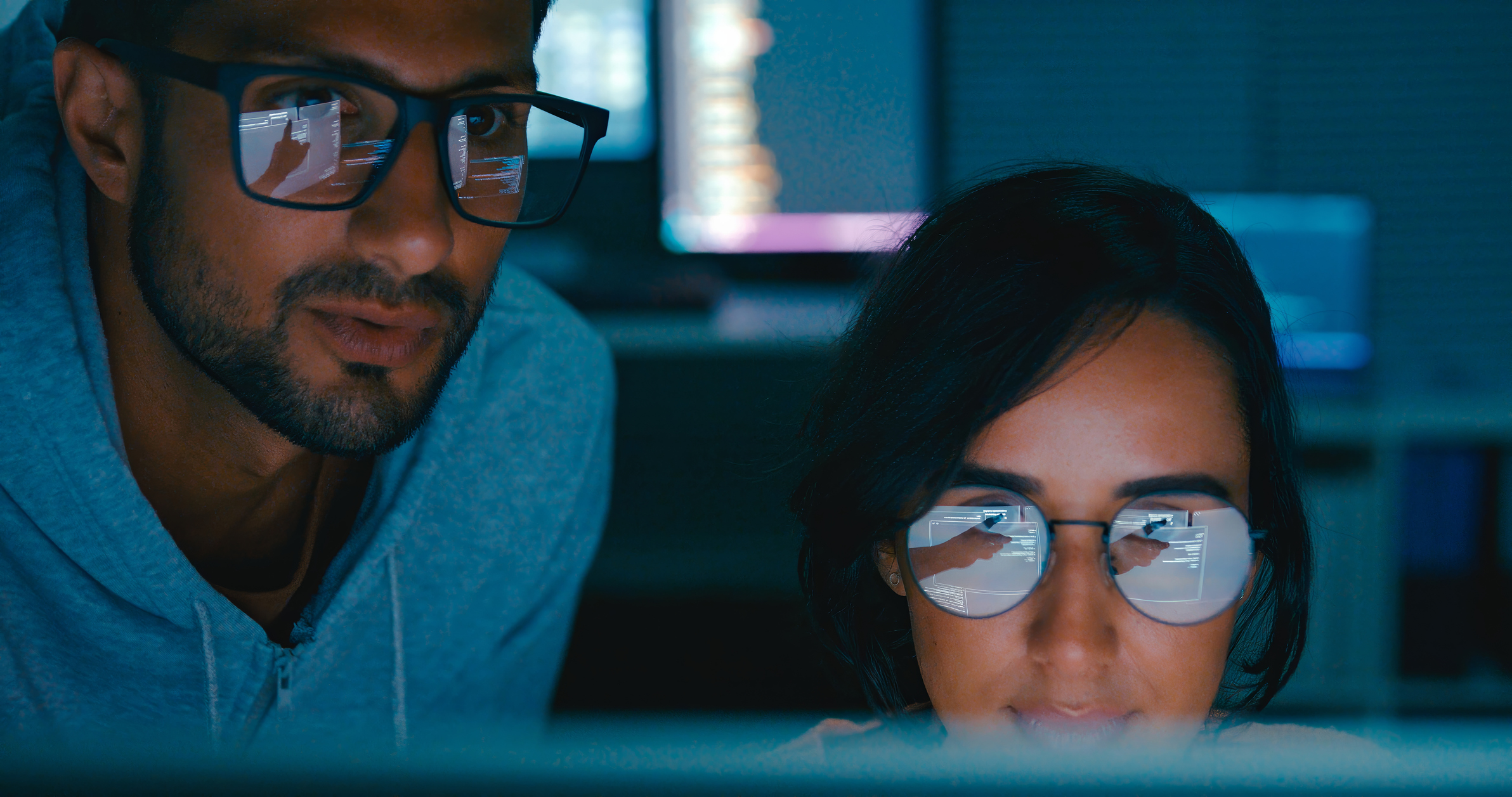 Closeup of Tech team professionals collaborate discuss software development strategies late night in modern office. Software developer, artificial intelligence and programming.