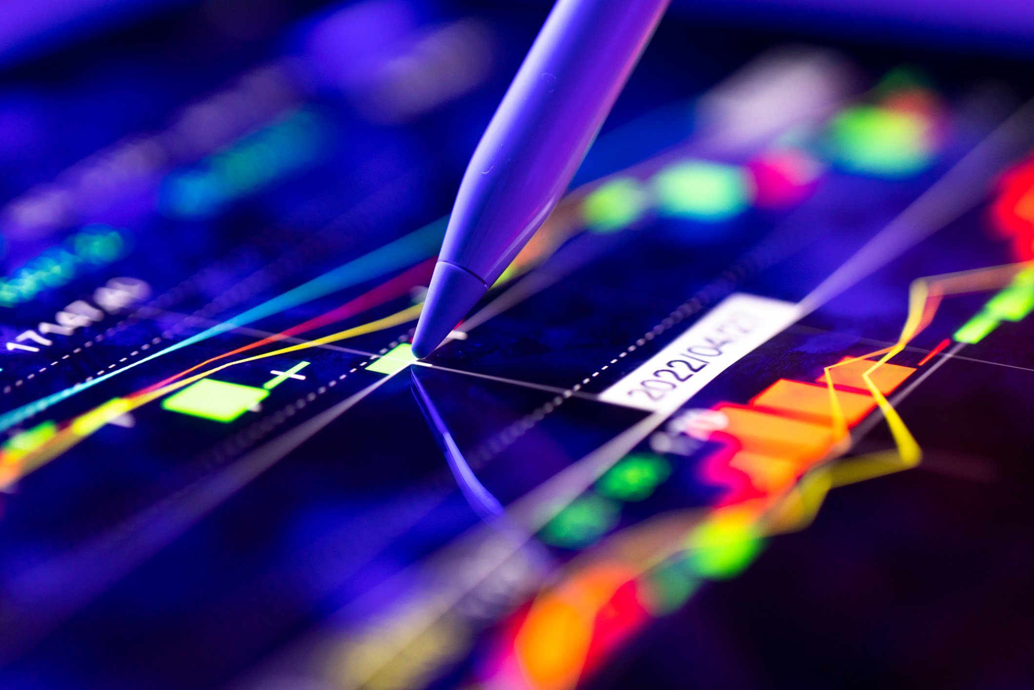 A business person tracking the technical movement of a stock chart on a computer screen.