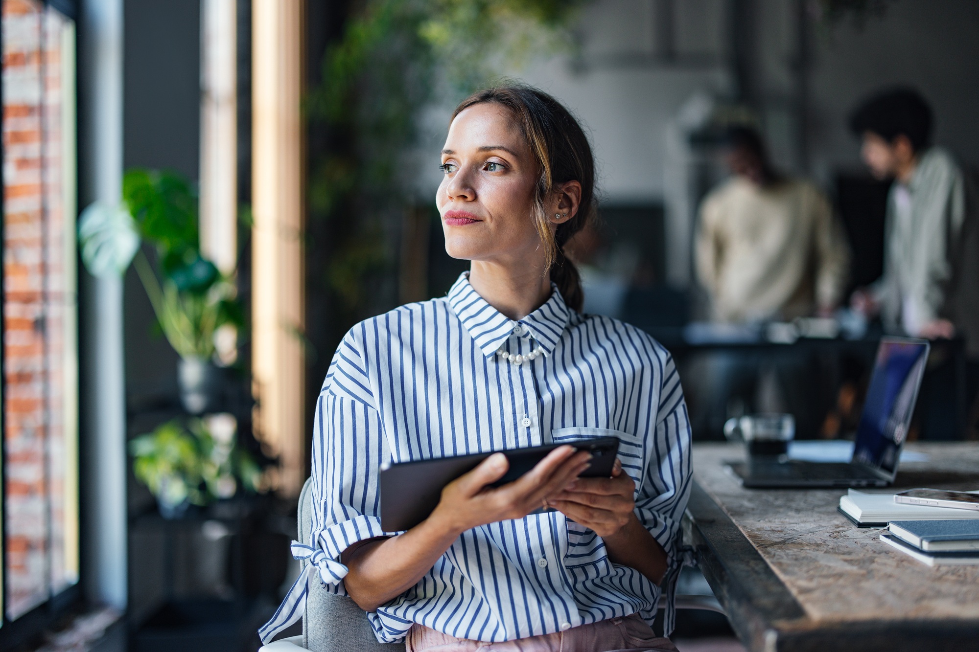 Professional Woman with Tablet Looking Thoughtful in Office