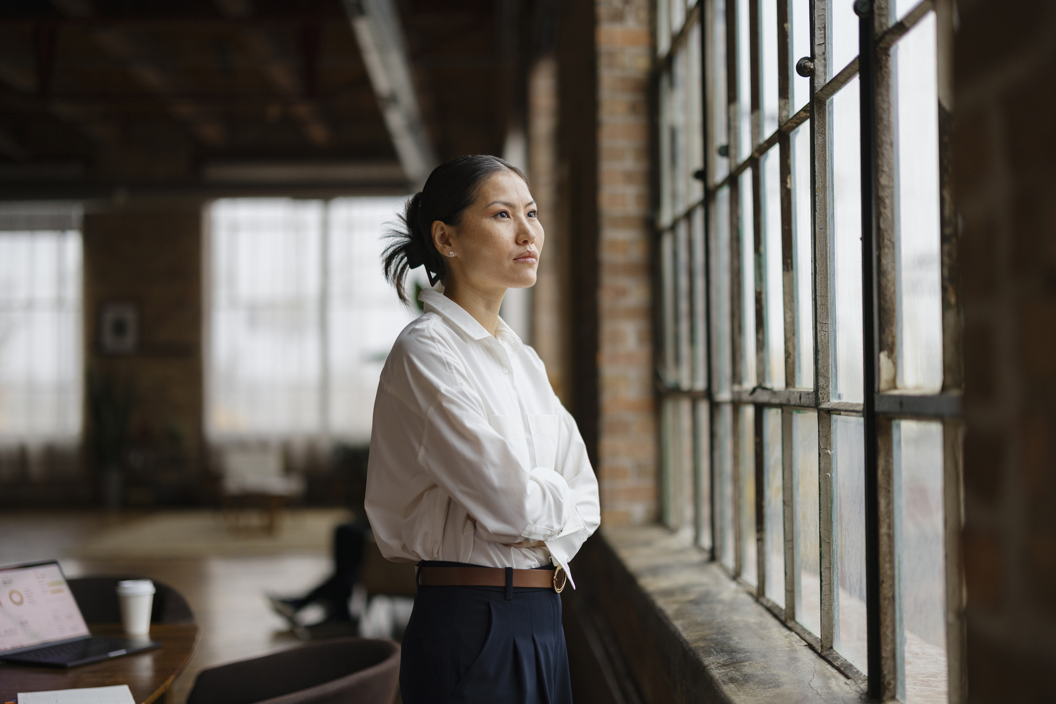 Thoughtful Asian female entrepreneur by the window in the office.